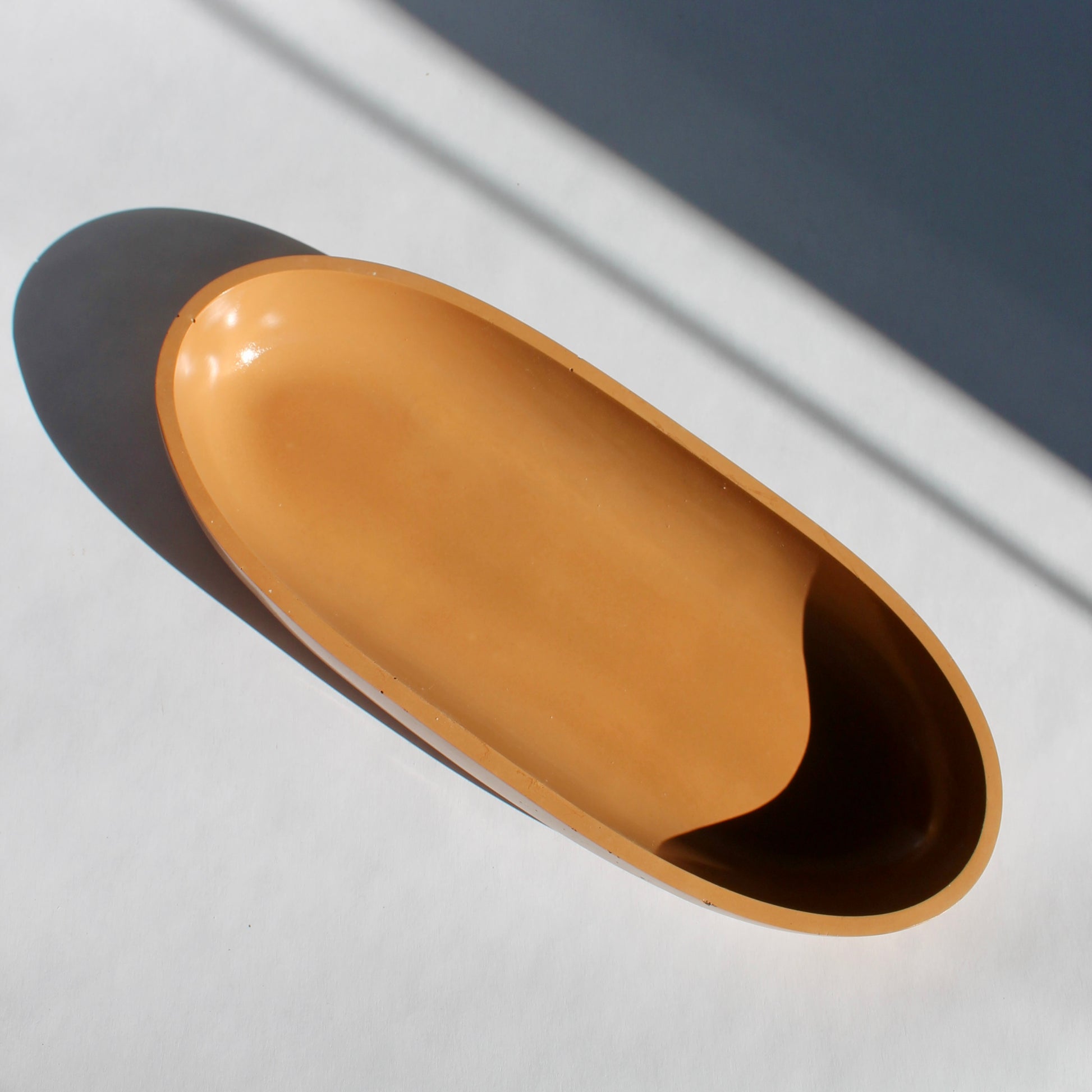 terracotta colored oval bowl on white background