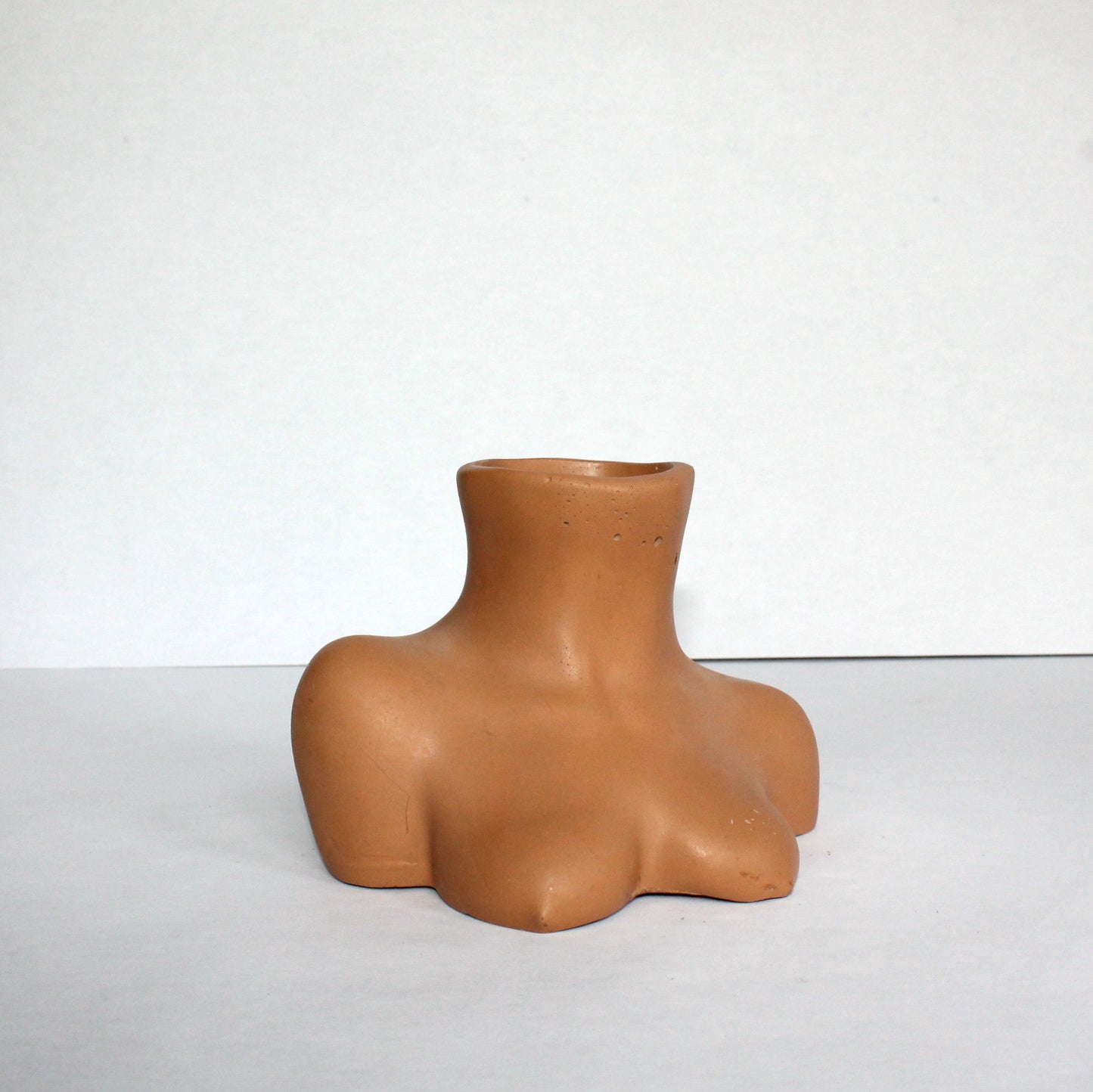 Terracotta concrete vase shaped like a female torso on a white background