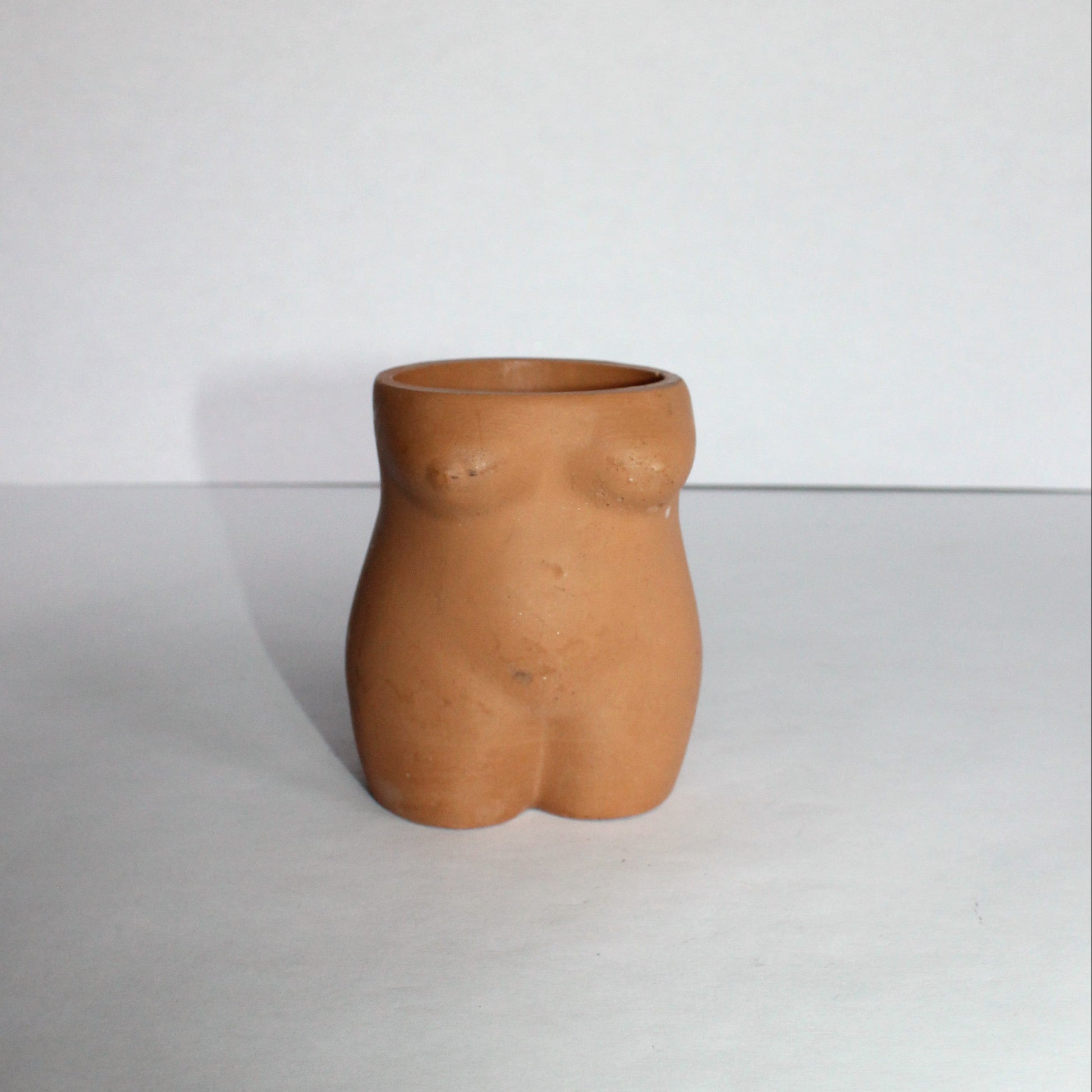 Concrete vase shaped like a torso on a white background