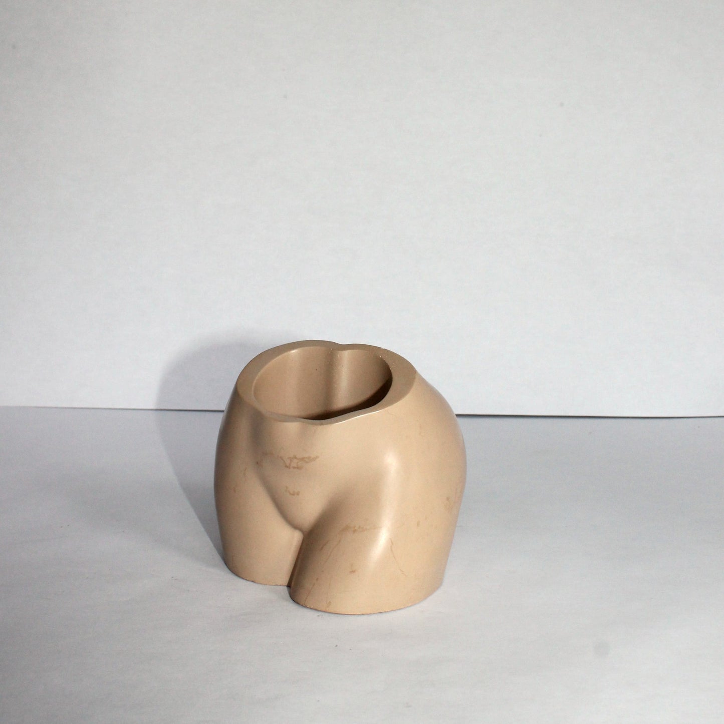 Beige concrete vase on a white surface with a white background