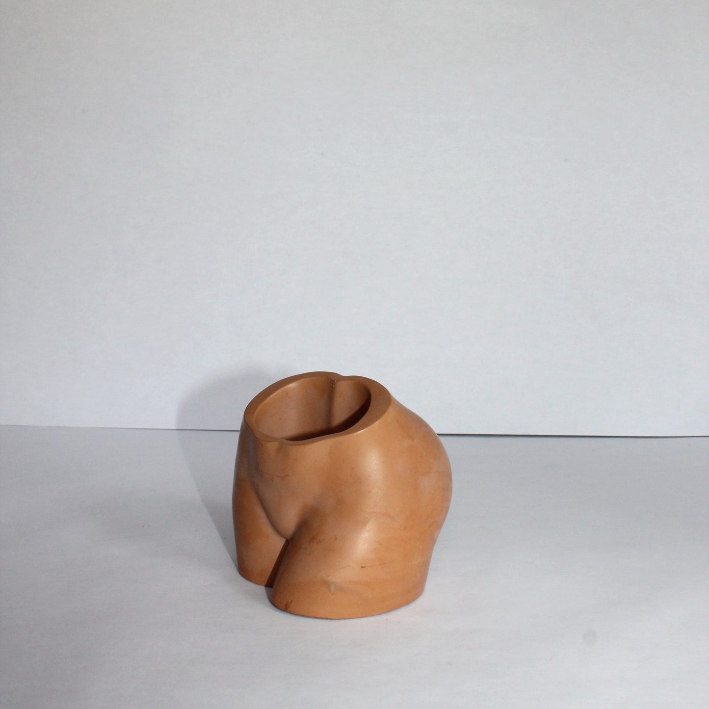concrete body shaped vase on a white surface with a white background