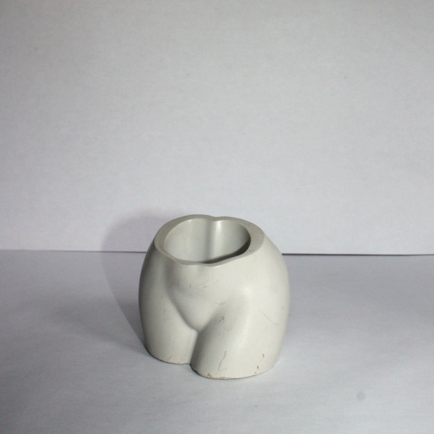 white ceramic vase on a white surface with a plain background