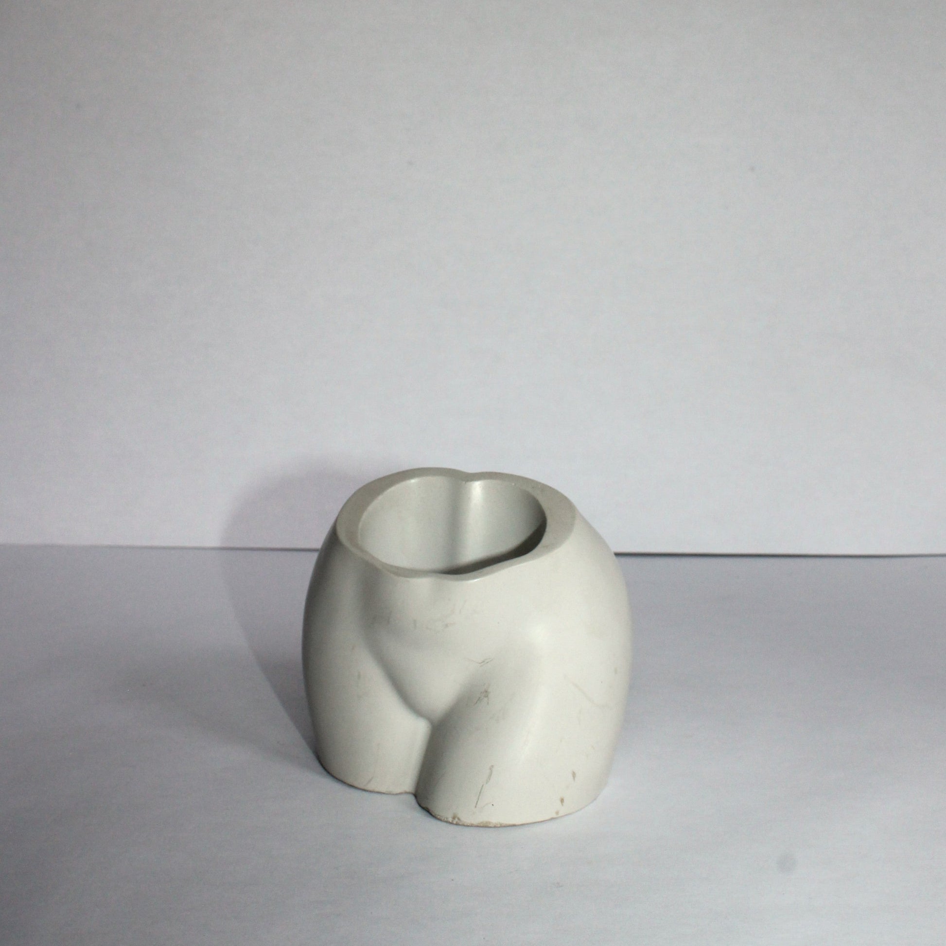 white ceramic vase on a white surface with a plain background