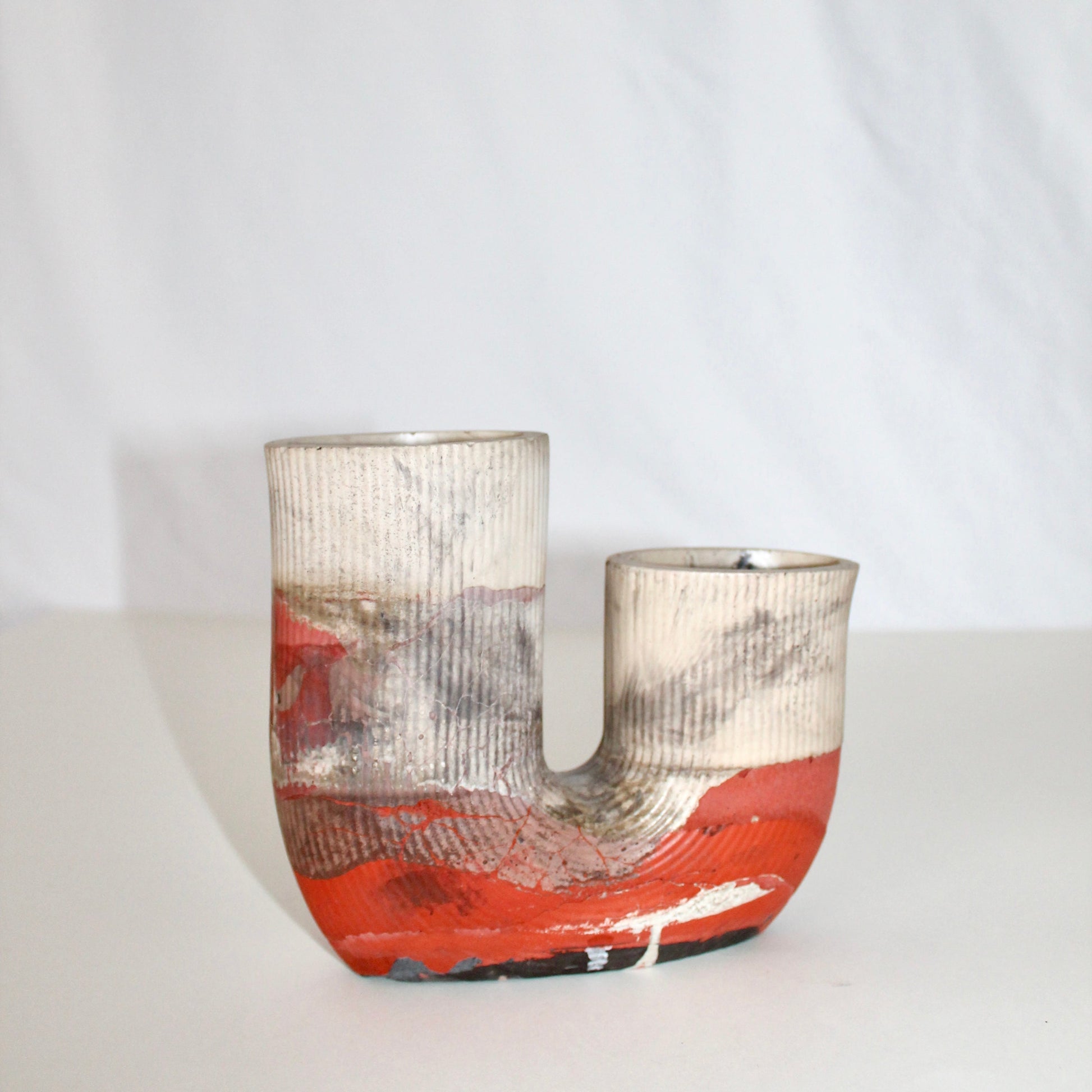 Concrete vase with orange and white abstract design on a white background