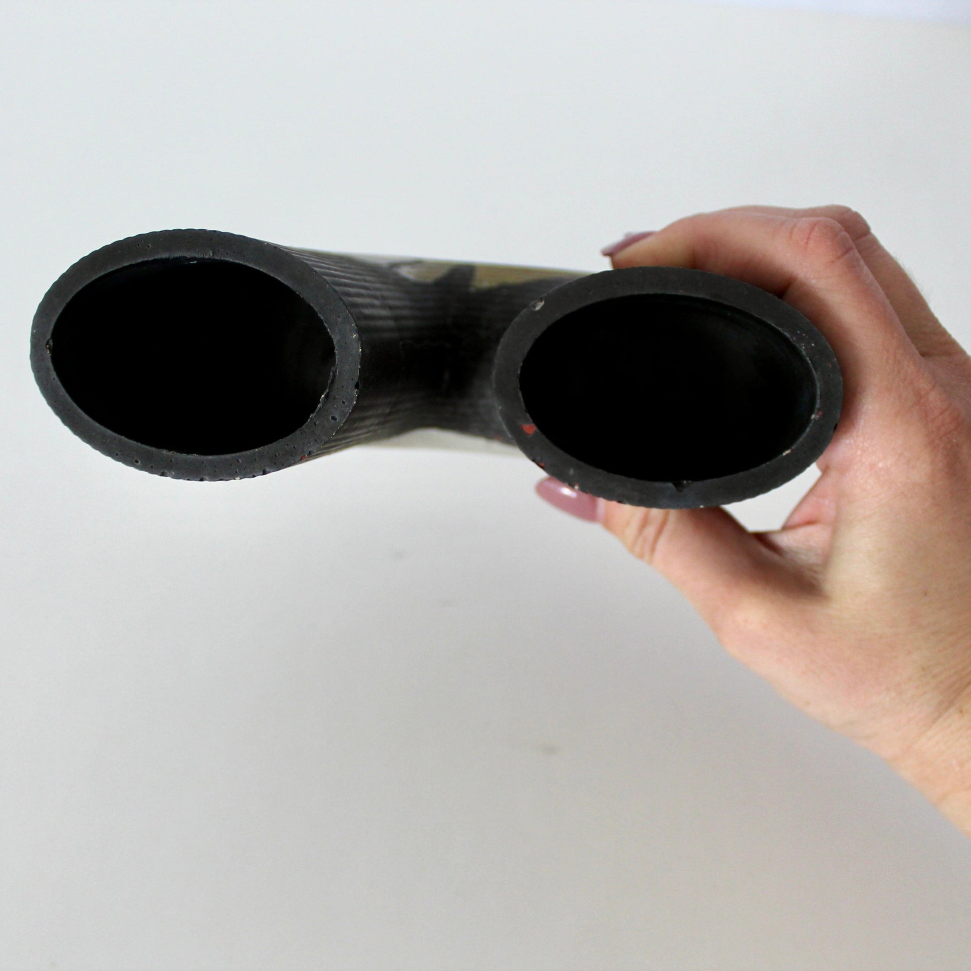 Hand holding a black cylindrical object against a white background